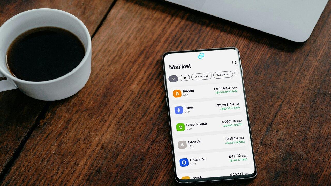 Cup of coffee beside a phone showing a crypto market app